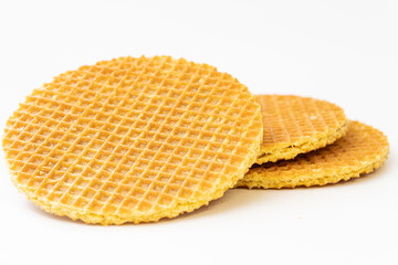 Close-up of three golden waffle cookies stacked on a white background. Perfect for concepts related to dessert, snacks, bakery products, and sweet treats