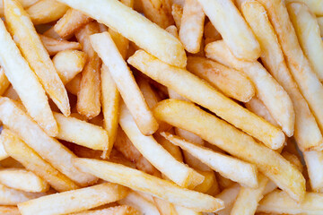 Close-up of golden, crispy French fries in a heap. Tasty deep-fried potato sticks, showcasing texture and seasoning. Popular fast food snack on a light background