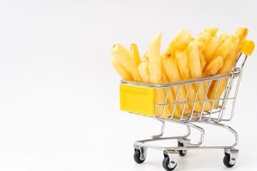 French fries in a small metal shopping cart on a white background. Conceptual image representing fast food, snacks, consumerism, or grocery shopping with humor and creativity