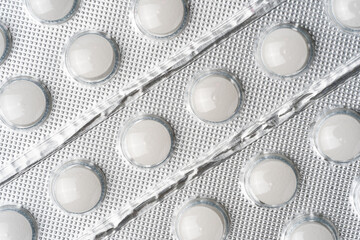 Close-up of white tablets in blister packaging. Medical background concept for healthcare, pharmaceuticals, prescriptions, medication, and modern drug manufacturing.