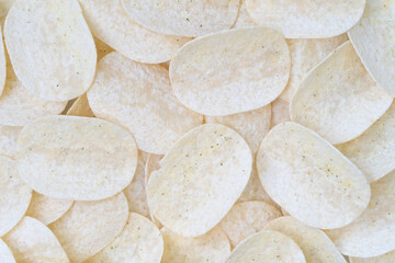Top view of many stacked potato chips with a light, crispy texture and seasoning. Ideal image for food packaging, snack promotions, or backgrounds in food advertisements