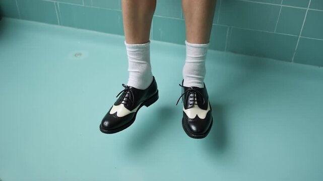 Two-tone Oxfords and White Socks Hovering Above a Turquoise Bathtub