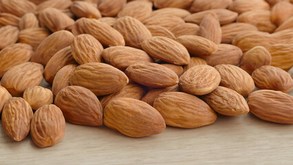 Almond nuts sprinkled on a square board on a wooden table.
