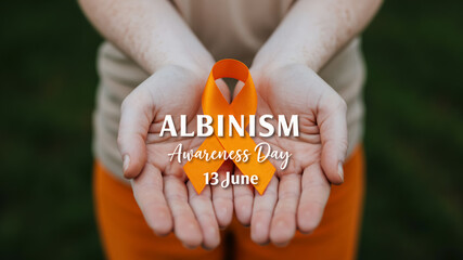 Albinism Awareness Day 13 June. Hands holding an orange awareness ribbon.