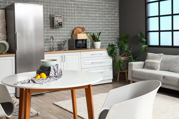 Interior of kitchen with stylish fridge, counters, sofa and table