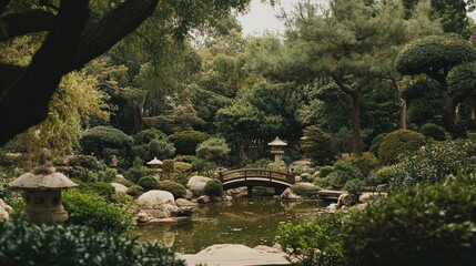 Tranquil Japanese garden with a small bridge over a pond. Lush greenery, rocks, and traditional lanterns