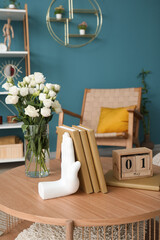 Stylish holder for books with vase of roses on table in room