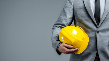 Symbolic image of safety and professionalism, male manager holding construction helmet, plain background