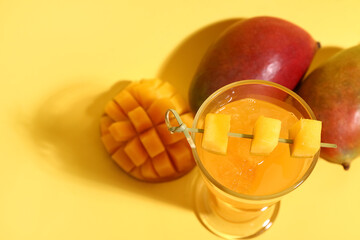 Glass of fresh mango smoothie on orange background, closeup