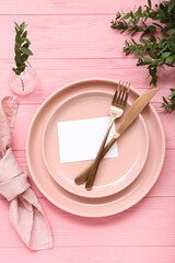 Stylish table setting with blank card and plant branches on pink wooden background