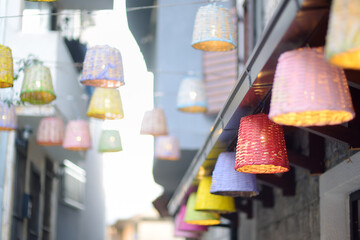 Decorative multicolor wicker lamps are hanging under the street in a small European town