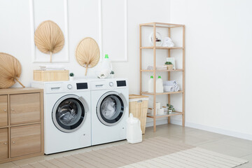 Interior of laundry room with washing machines, wooden cabinet and shelving unit
