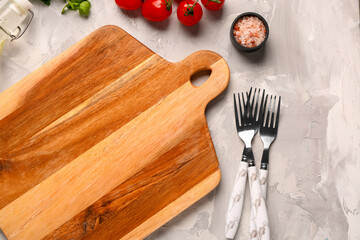 Wooden cutting board, forks and sea salt on light background, closeup