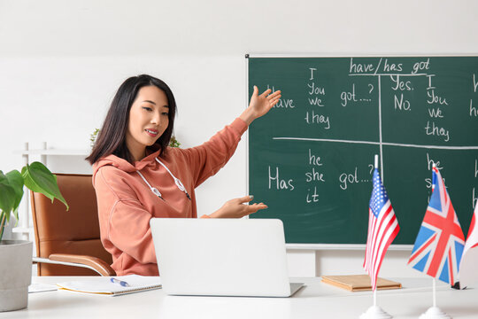 Female English teacher giving online grammar lesson in classroom - Powered by Adobe