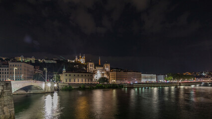 Fototapeta premium Panorama showing night timelapse of Lyon's cityscape with the red suspension footbridge over the Saone River. France