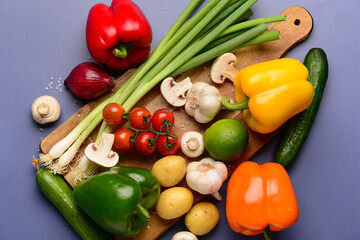 Wooden board with fresh vegetables, fruits and mushrooms on blue background