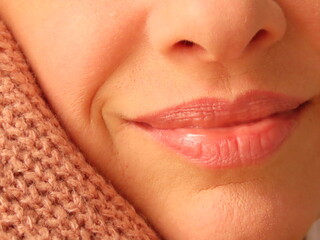 Closeup of woman face leaning on light pink cozy sweater. Woman enjoying warm and cozy winter clothes. 