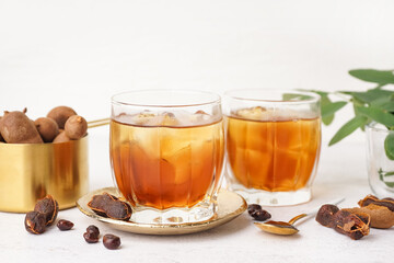 Glasses of tasty tamarind drink and fruits on white background