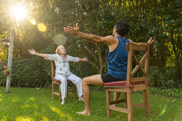 Senior woman and physiotherapist doing seated exercises outdoors