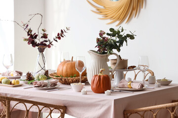 Autumn table setting decorated for Thanksgiving Day with pumpkins and eucalyptus branches in light dining room