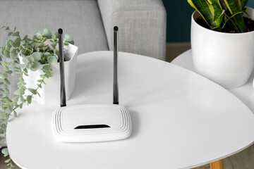 Modern wi-fi router and plant on table in living room, closeup
