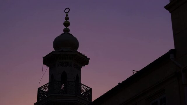 Minaret silhouetted against changing sky at twilight