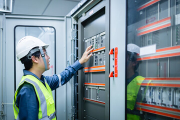 Electrical engineer is performing inspection with control panel inside substation control room ensuring safety and functionality of equipment with focused attention