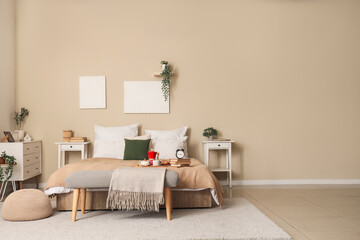 Interior of stylish bedroom with tables, bench and breakfast on bed