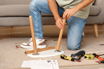 Young man assembling small table at home, closeup