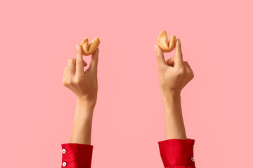 Female hands holding fortune cookies on pink background, closeup