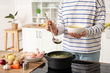 Young woman pouring soup into bowl in kitchen, closeup