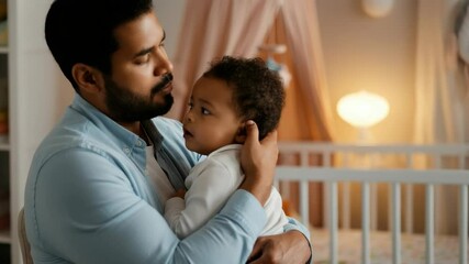 Caring father holding and comforting his baby in cozy nursery