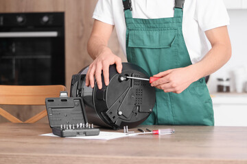 Male technician tightening screw in modern multi cooker with screwdriver