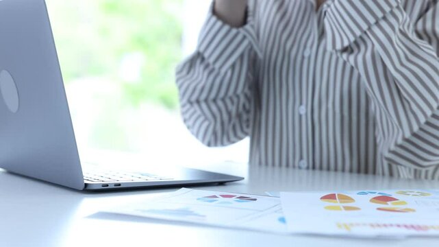 Woman putting on glasses while working on laptop at desk indoors, closeup