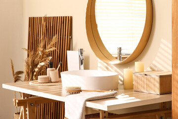 Table with sink, box and bath supplies near beige wall in bathroom