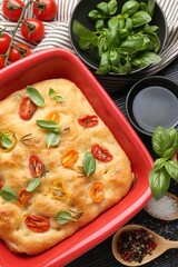 Delicious focaccia with tomatoes, spices and oil on table, flat lay