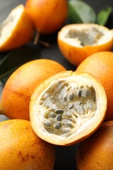 Ripe passion fruits and leaves on table, closeup