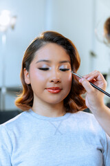 Makeup artist applying makeup to young woman's face