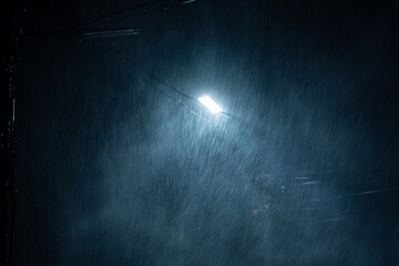 Falling raindrops on night background.Heavy rainy and wind with public street lights on black...