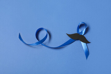 Blue ribbon with paper mustache on color background. Prostate cancer awareness concept