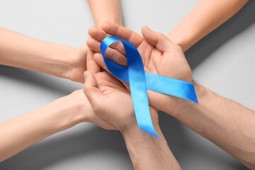 Hands with blue ribbon on grey background. Prostate cancer awareness concept