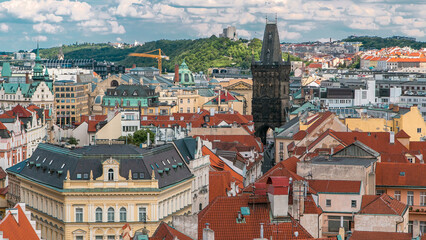Fototapeta premium Aerial view of the traditional red roofs of the city of Prague, Czech Republic with the Powder tower and Vitkov Hill in the distance timelapse.