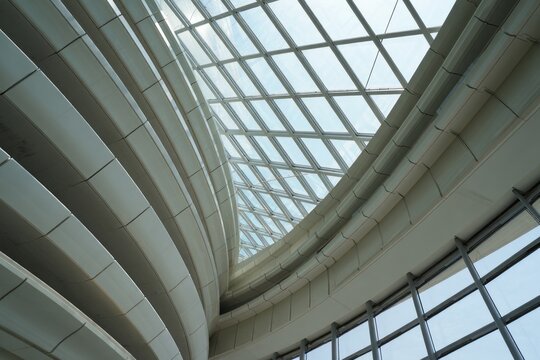 curved modern architectural interior with large glass ceiling allowing natural light to enter bright and spacious space - Powered by Adobe