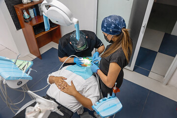 Dentist and assistant performing a dental procedure on a patient in a modern clinic. Professional...