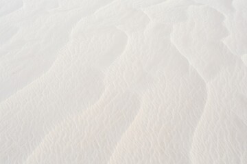 Obraz premium Close-up view of white sand with delicate wind-formed ripples and soft shadows creating a peaceful natural pattern