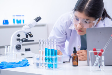 Teen scientist girl conducting science test by carefully evaluating blue solution in laboratory....