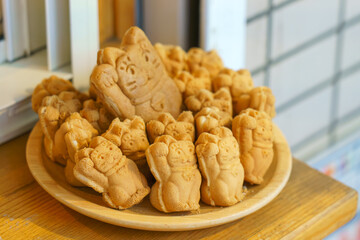 Tokyo, Japan - Sep 30 2024, A close-up view of a bowl filled with Taiyaki pies in the form of a Maneki Neko, in the window of a cafe, Tokyo, Japan
