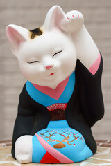Tokyo, Japan - Sep 30 2024, vertical view of the sculpture of a seated smiling beckoning cat Maneki Neko dressed in a black and blue kimono, Tokyo, Japan