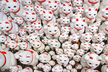 Tokyo, Japan - Sep 30 2024, A close-up view of many multi-sized white beckoning cat figure of Maneki neko with red ears and noses displayed at Gotokuji Temple, without people, at daytime, Tokyo, Japan