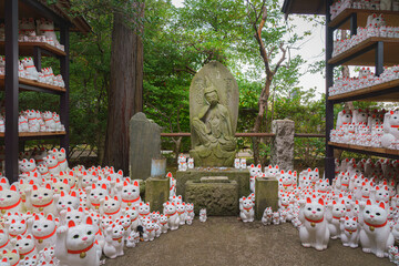 Tokyo, Japan - Sep 30 2024, view of the Buddha statue surrounded by many different-sized figures of beckoning cats Maneki Neko, at Gotokuji Temple, without people, at daytime, Tokyo, Japan